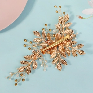 Detail of luxury bridal hair clip featuring golden leaves and elegant white pearls