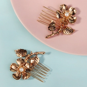 Detail of golden metal floral hair combs with white pearl centers and leaf patterns
