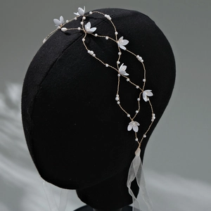Dettaglio della fascia da sposa con fiori bianchi, perle e nastri di tulle