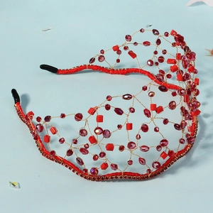 Detailed macro view of handmade red crystal beads on a golden mesh bridal headband