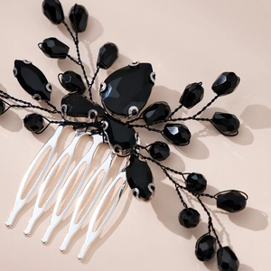 Macro detail of gothic bridal hair comb with black crystals and pearl accents on silver teeth