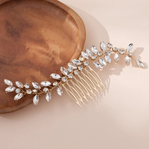 Detailed macro view of golden metal vine hair comb with leaf-shaped crystal rhinestones