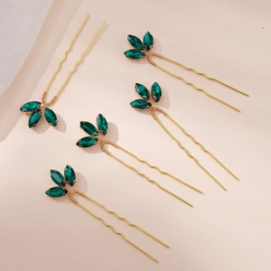 Detail of five golden U-shaped hairpins with green crystal leaf decorations for bridal hair