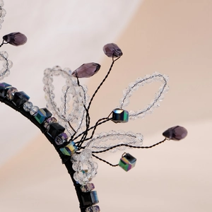 Macro detail of handmade crystal headband featuring purple droplets and beaded flower weaving