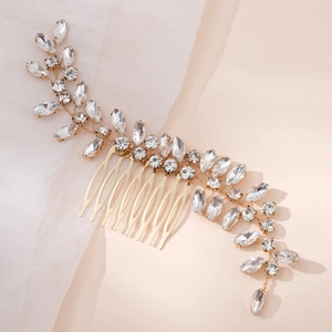 Elegant gold bridal hair comb with crystal leaves and rhinestones on a soft background