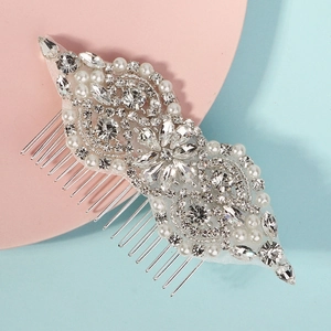 Close-up of bridal hair comb with shimmering rhinestones and white pearls on silver base