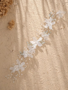 Detailed macro of white chiffon flowers and artificial pearl beads on a bridal hair vine