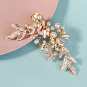 Elegant gold bridal hair clip with white pearls and leaf accents on a colorful background