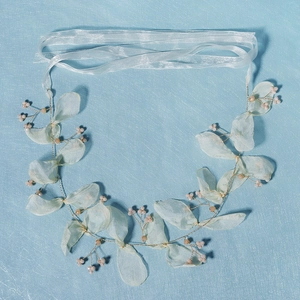 Detailed macro view of mint fabric leaves and pink beads on a bridal hairband