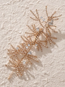 Macro shot of gold bridal hair clip with sparkling rhinestones and crystal branch design