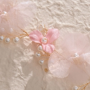 Detail of pink mesh fabric flowers and white pearls on golden wire bridal headband