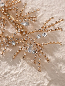 Macro shot of bridal gold hair clip with sparkling rhinestones and crystal branch details