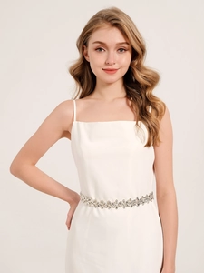 Detailed view of an elegant rhinestone flower belt on a white bridal wedding dress