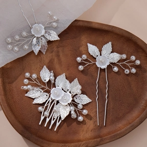 Detailed set of silver leaf hair pins and comb with white pearls on a wooden tray