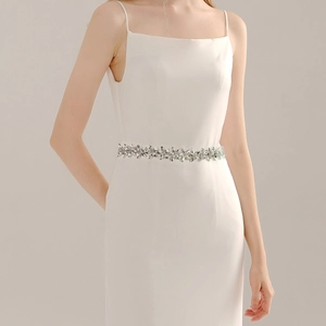 Close-up of bridal dress belt featuring silver metal flowers and sparkling rhinestones