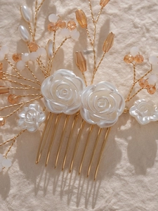 Macro shot of white resin camellia bridal hair comb with golden crystal details