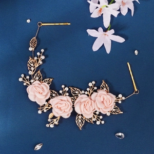 Detail of bridal headband with fabric roses, crystals, and gold leaves on blue background