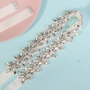 Detail view of crystal rhinestone leaf patterns on a white bridal wedding dress belt