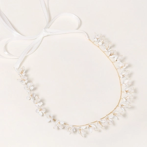 Détail d'un bandeau de mariée avec fleurs blanches, fil doré et rubans de soie blancs