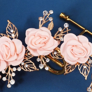 Detail shot of handmade pink satin roses and gold leaf bridal headband with crystals