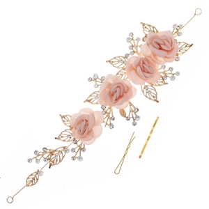 Detail view of handmade pink silk roses with gold leaves and rhinestones on the headband