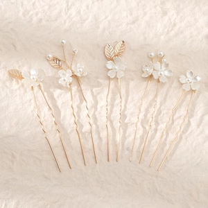 Detailed close-up of handmade bridal hairpins with white flowers and golden leaves