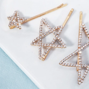 Tres horquillas de estrella dorada con diamantes de imitación en fondo de mármol