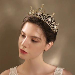 Detail of luxury gold baroque crown with colorful crystals worn by a model in a lace dress
