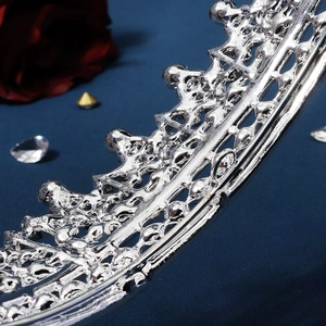 Baroque silver alloy bridal crown with rhinestones shown on a deep blue textured background