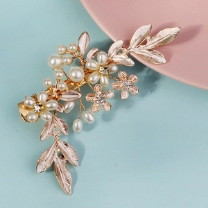 Detail of floral bridal hair clip with white enamel leaves and pearls on gold metal