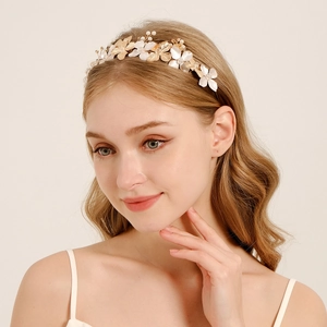 Detail of bridal headband with light gold leaves, white flowers, and pearls on a model