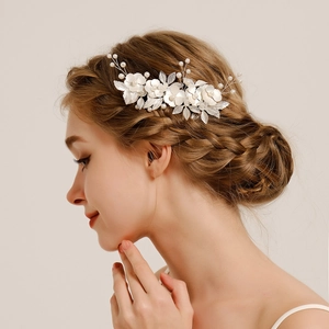 Détail d'un peigne à cheveux de mariée avec fleurs blanches, perles et feuilles d'argent