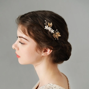 Macro view of handmade gold leaves and white pearl bridal hair comb for weddings