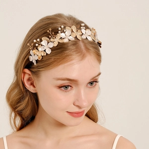 Detail of bridal headband with creamy flowers, gold leaves, and elegant pearls on model