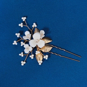 Détail d'épingle à cheveux fleur en céramique faite main avec pétales blancs et dorés