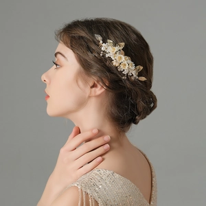 Detailed view of handmade gold bridal hair comb with pearls and white floral elements