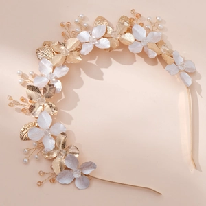 Floral bridal headband with gold metal petals and pearls on a warm pink background