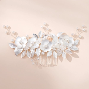 Détail d'un peigne de mariée argenté avec fleurs blanches mates, perles et feuilles