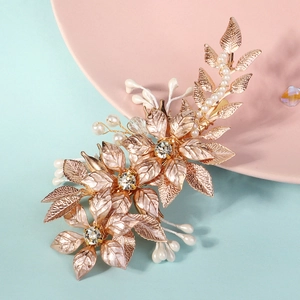 Macro detail of rose gold floral hair clip with white pearls and delicate leaf petals