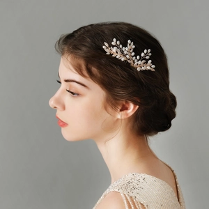 Detail of a handmade gold pearl hair comb worn by a model in a champagne sequin dress