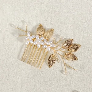 Detailed close-up of handmade gold hair comb with pearl flowers and intricate metal leaves
