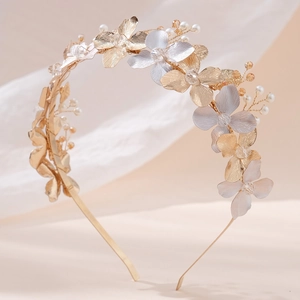 Elegant floral metal headband with crystal and pearl accents on light beige background