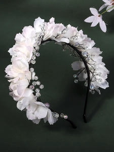 Detailed macro of white floral headband with transparent beads on dark background
