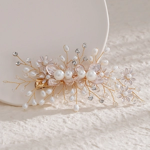 Close-up of handmade floral hair clip with cream pearls and rhinestones on gold wire