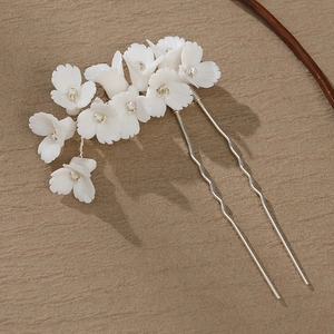 Détail d'une épingle à cheveux fleur en céramique blanche faite main avec strass et broches