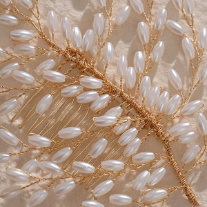 Macro detail of handmade gold wire woven bridal hair comb with elegant white pearls