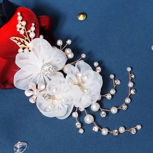 Detail of bridal hairband featuring tulle flowers, pearls, and gold leaf decorations
