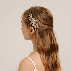 Close-up of bridal hair clip with gold leaves and sparkling crystal flowers on model