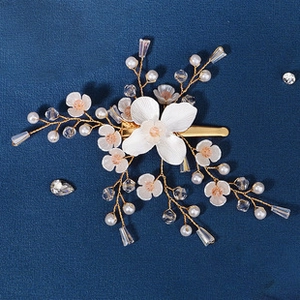 Close-up of bridal hair clip with white resin flowers, pearls and crystal beads