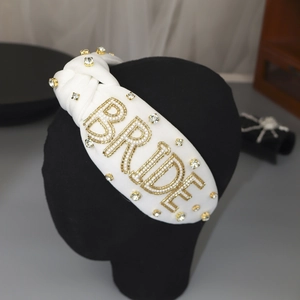 Detailaufnahme des weißen Haarreifens mit BRIDE-Schriftzug und glitzernden Strasssteinen